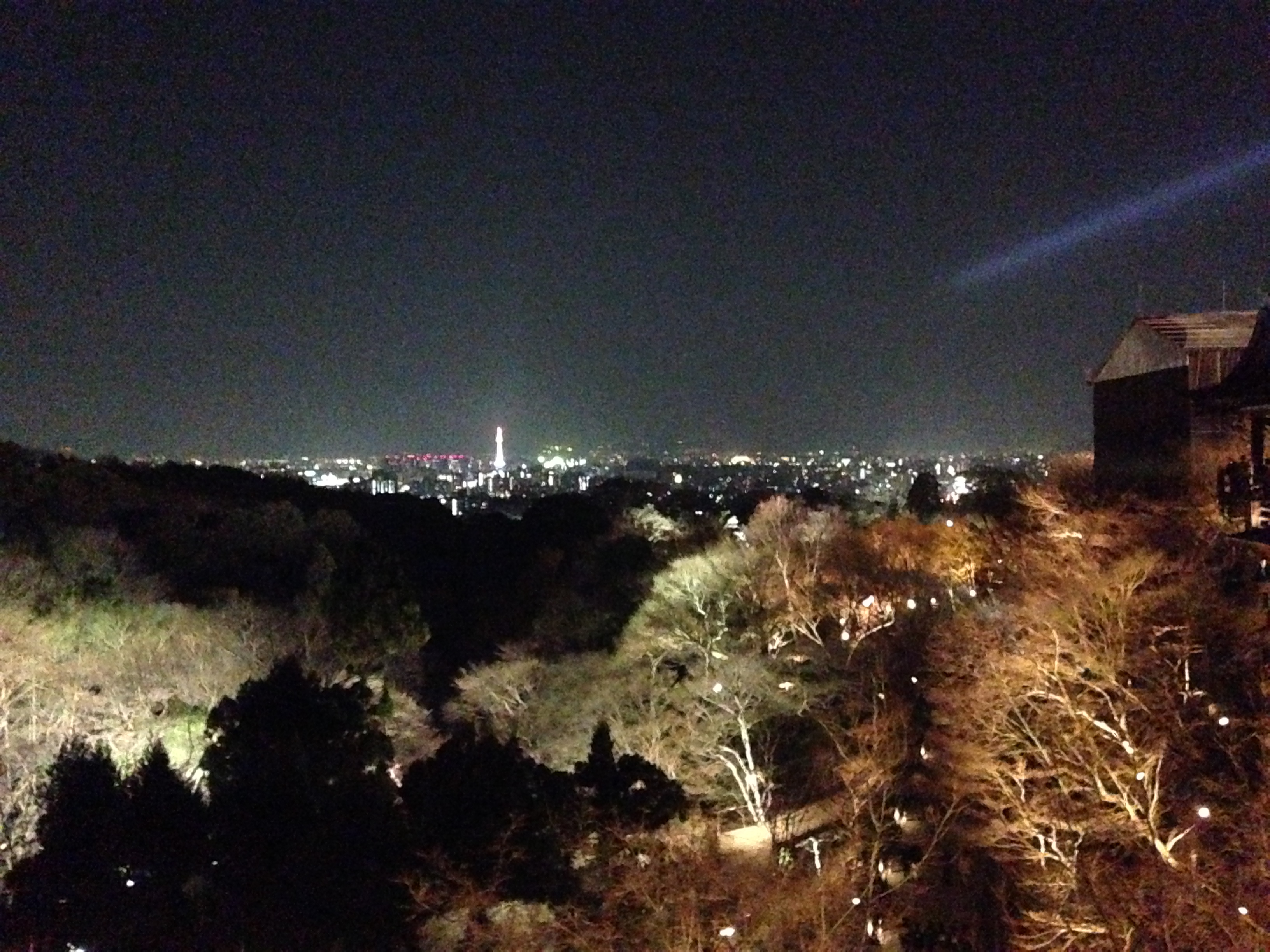 Kiyomizu-dera illuminated at night above the city lights of Kyoto