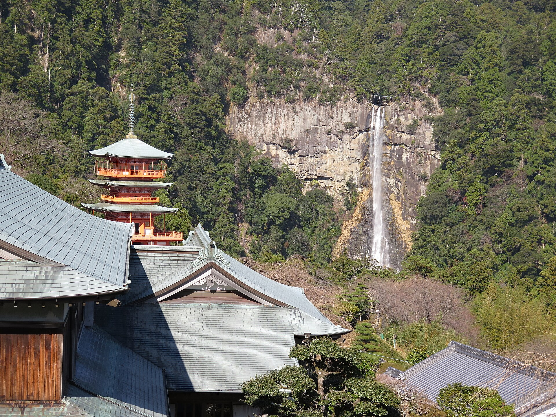 The vermilion halls of Kumano Nachi Taisha with Nachi Falls beyond