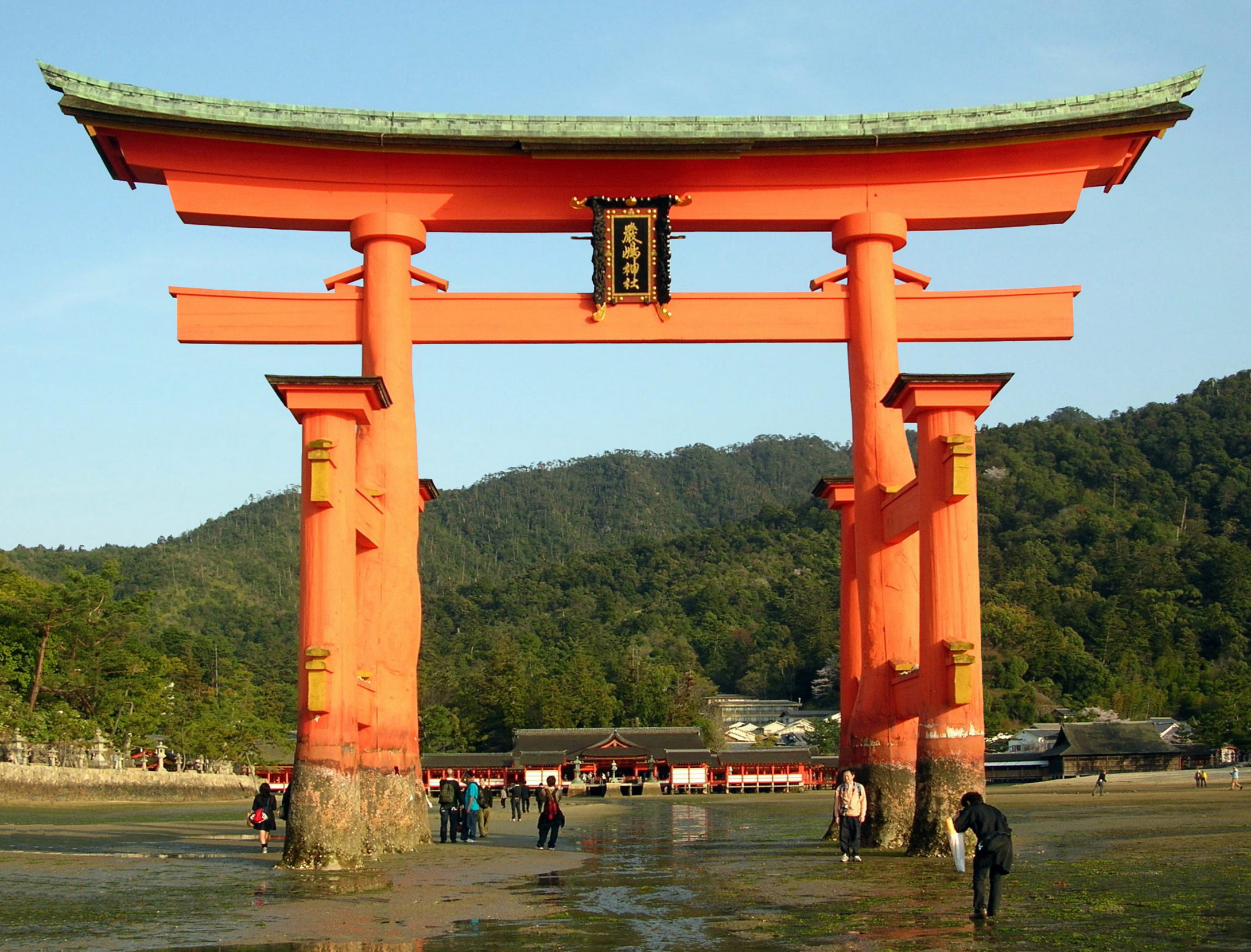 The vermilion corridors of Itsukushima Shrine built over the water with the torii beyond