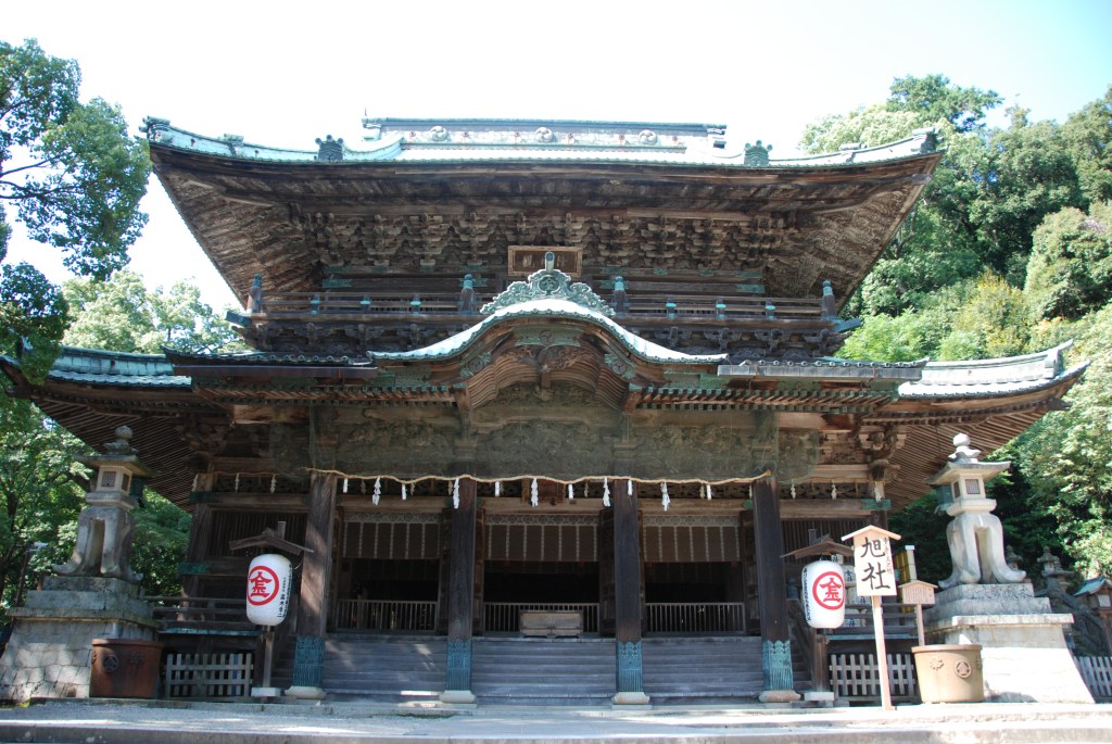 Front of the Asahi-sha at Kotohira-gu, a large two-story wooden shrine hall with a heavy curved roof and carved eaves, at the top of a short flight of stone steps
