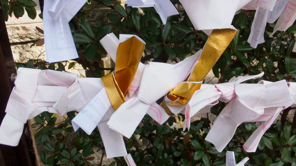Many folded omikuji fortune slips tied up at Zeniarai Benzaiten Shrine in Kamakura